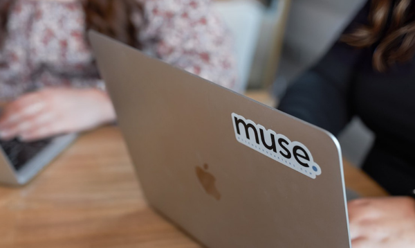 two coworkers typing on their laptops at a table